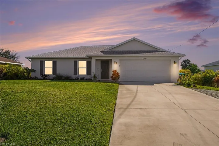 Single story home with stucco siding, driveway, a front yard, and a garage