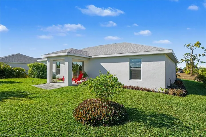 Rear view of property featuring stucco siding, a patio, and a lawn