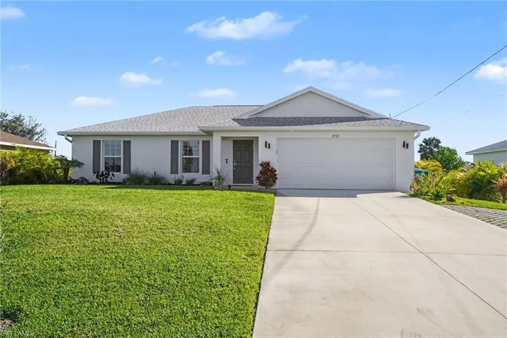 Ranch-style house with stucco siding, a front yard, and driveway