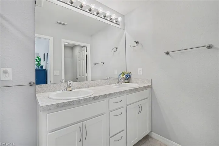 Full bathroom with a textured wall and double vanity