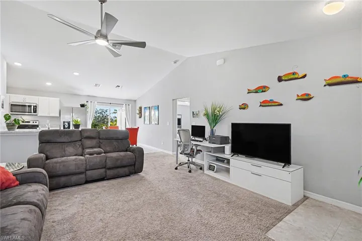 Living area with light colored carpet, vaulted ceiling, a ceiling fan, a desk, and recessed lighting