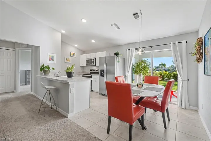 Dining area with lofted ceiling, light carpet, light tile patterned floors, and recessed lighting