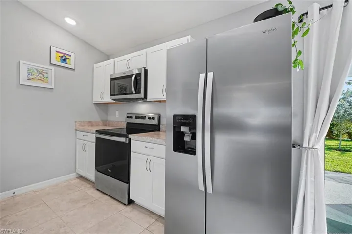 Kitchen featuring stainless steel appliances, light countertops, white cabinets, light tile patterned floors, and recessed lighting
