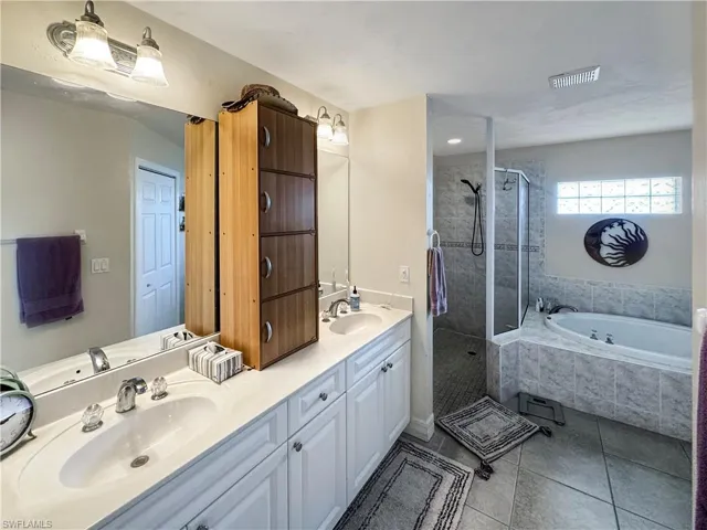 Bathroom with a tile shower, double vanity, a garden tub, and tile patterned flooring