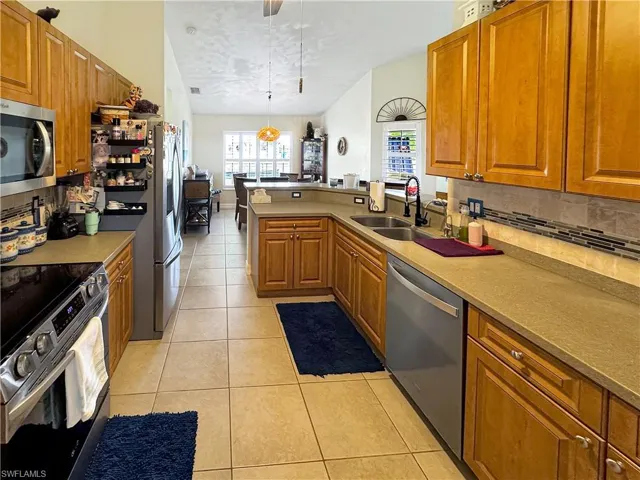 Kitchen featuring appliances with stainless steel finishes, decorative backsplash, brown cabinetry, and a textured ceiling