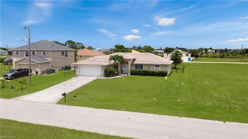 Ranch-style house with driveway, an attached garage, and a front lawn
