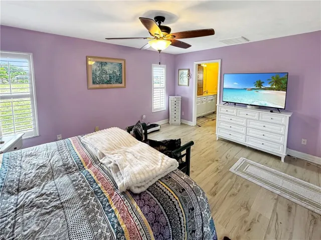 Bedroom featuring light wood-style flooring, a ceiling fan, and ensuite bathroom