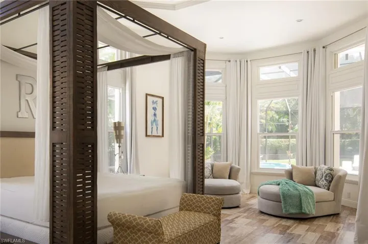 Living area with a wealth of natural light, wood-type flooring, and crown molding