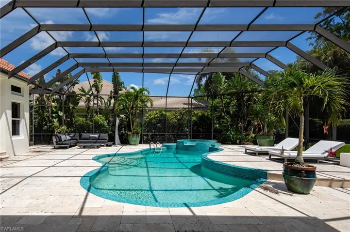 View of swimming pool featuring glass enclosure, a patio, and an outdoor hangout area
