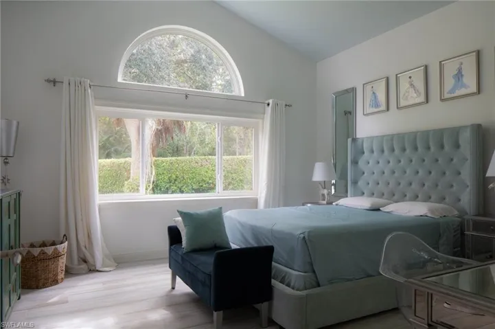Bedroom with multiple windows, vaulted ceiling, and light hardwood / wood-style flooring