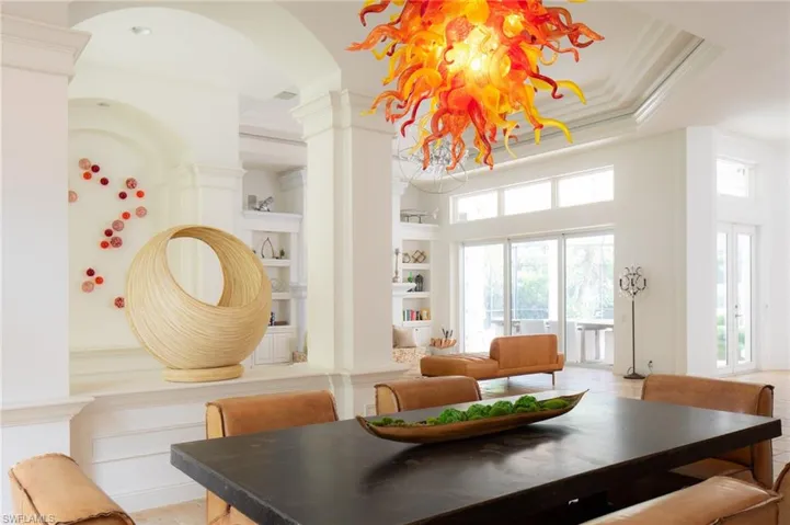 Dining room featuring built in features, crown molding, a raised ceiling, a high ceiling, and decorative columns