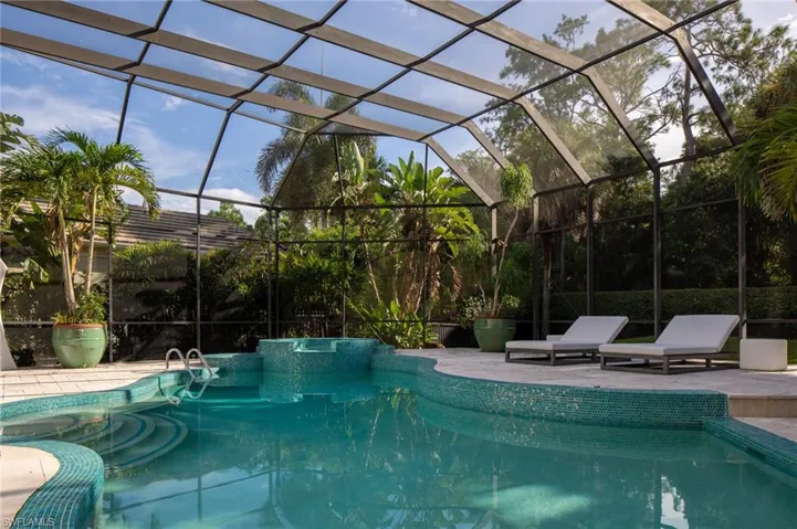 View of swimming pool with glass enclosure and a patio