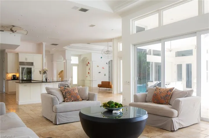 Living room with an inviting chandelier, a wealth of natural light, a towering ceiling, and crown molding