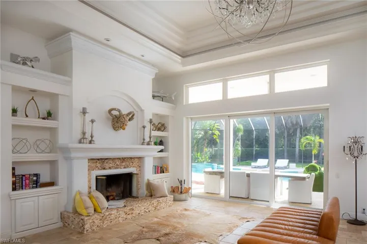 Living room featuring built in shelves, a fireplace, ornamental molding, and a towering ceiling