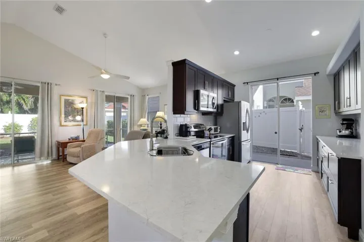 Kitchen featuring sink, a healthy amount of sunlight, vaulted ceiling, and appliances with stainless steel finishes