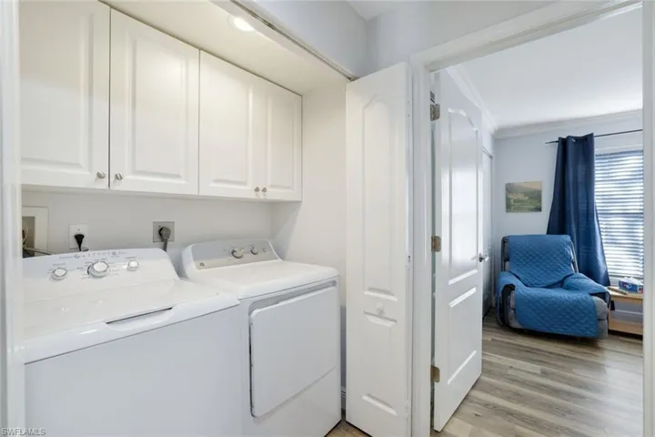 Laundry room with washer and clothes dryer, cabinets, crown molding, and light hardwood / wood-style flooring