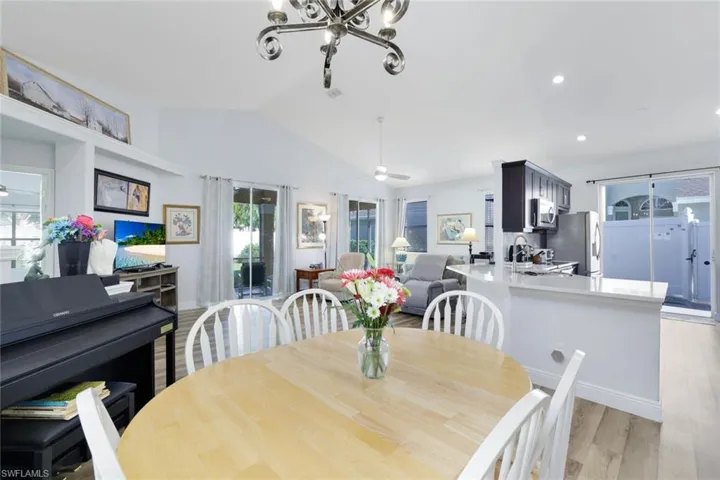 Dining area featuring light wood-type flooring, ceiling fan with notable chandelier, a wealth of natural light, and lofted ceiling