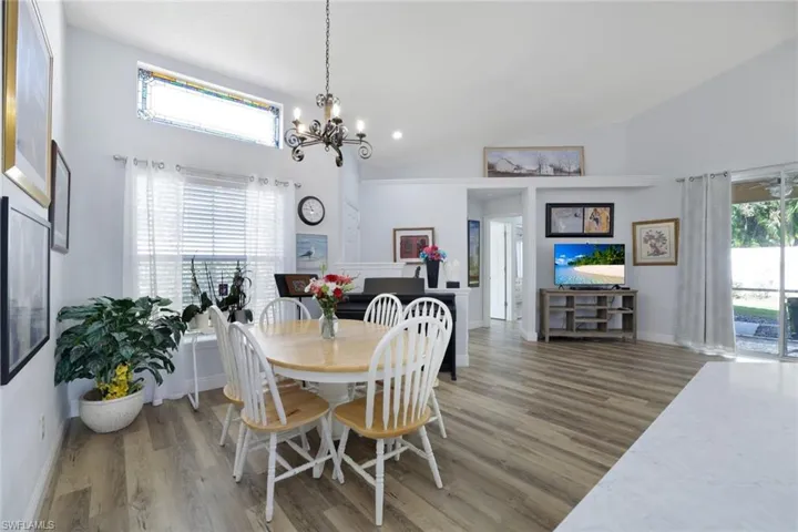 Dining area with dark hardwood / wood-style flooring, high vaulted ceiling, and a notable chandelier