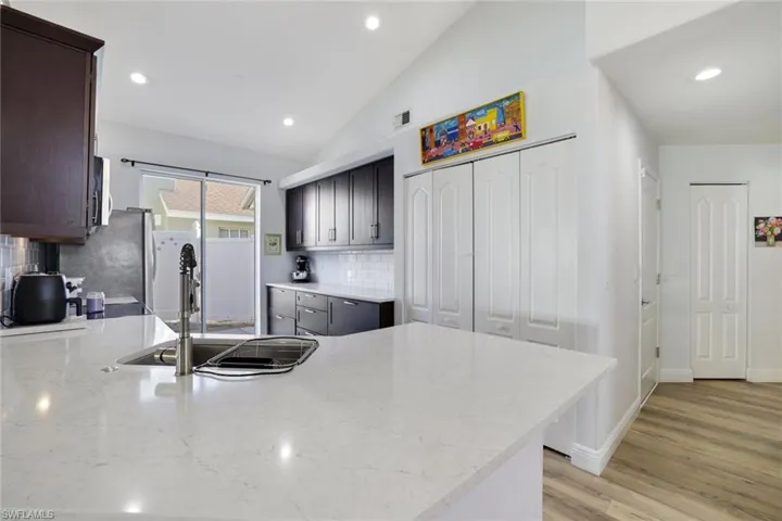 Kitchen with lofted ceiling, backsplash, sink, light hardwood / wood-style flooring, and kitchen peninsula