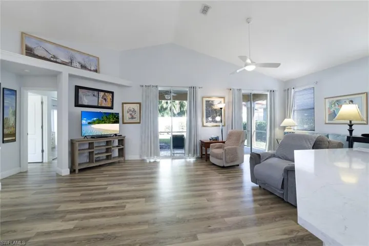 Living room featuring ceiling fan, dark hardwood / wood-style flooring, and lofted ceiling