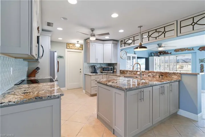 Kitchen featuring visible vents, appliances with stainless steel finishes, a ceiling fan, a sink, and a peninsula