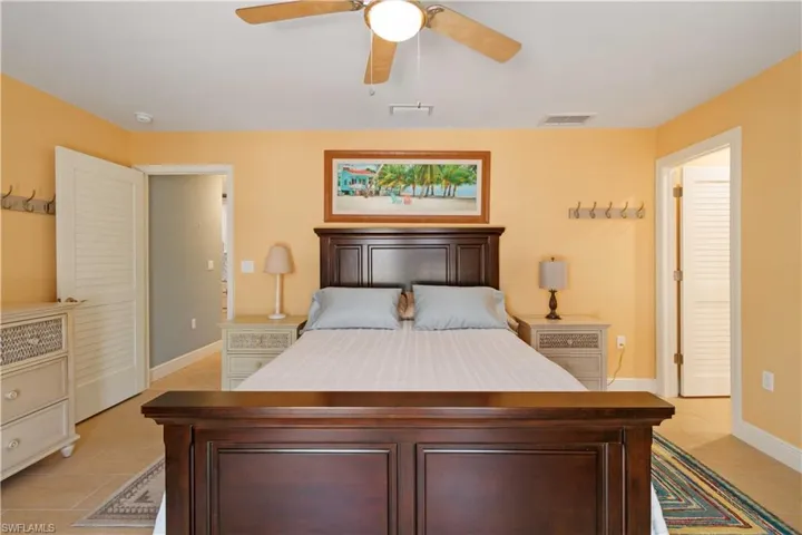 Bedroom featuring light tile patterned floors, baseboards, visible vents, and a ceiling fan