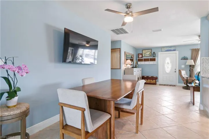 Dining space featuring light tile patterned floors, a ceiling fan, visible vents, and baseboards