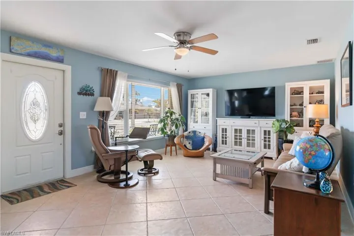 Tiled living room featuring baseboards, visible vents, and a ceiling fan