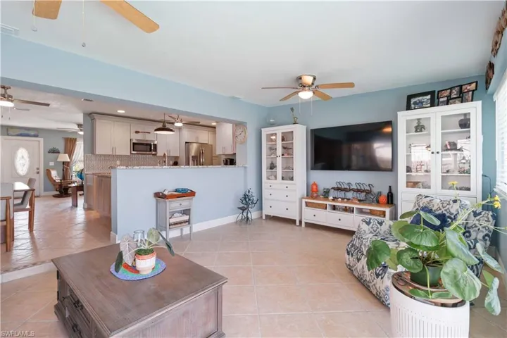 Living room with light tile patterned floors, ceiling fan, and baseboards