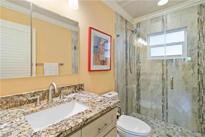 Bathroom with ornamental molding, a stall shower, vanity, and toilet