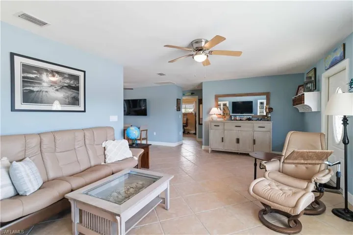 Living room with visible vents, ceiling fan, baseboards, and light tile patterned flooring