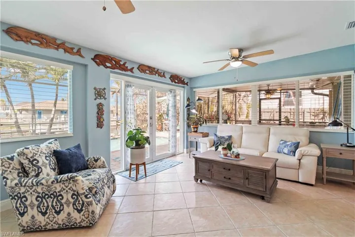 Living room with visible vents, light tile patterned flooring, a ceiling fan, and a healthy amount of sunlight