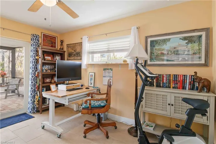 Home office featuring baseboards, a ceiling fan, and light tile patterned flooring