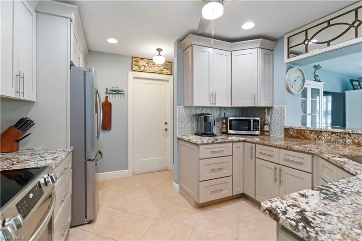 Kitchen with light tile patterned floors, light stone counters, recessed lighting, stainless steel appliances, and backsplash