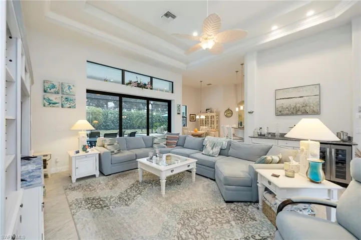 Living room featuring a towering ceiling, wine cooler, a ceiling fan, crown molding, and tile patterned flooring