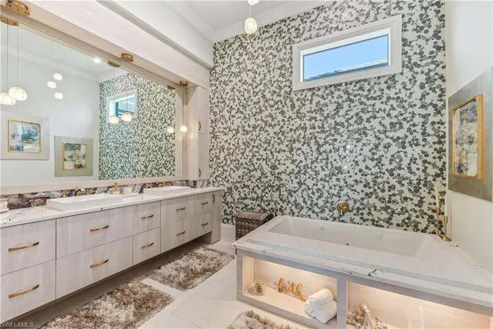Bathroom with tile patterned floors, vanity, crown molding, and tile walls