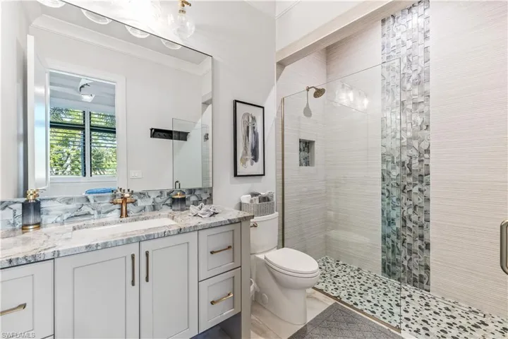 Bathroom with crown molding, vanity, a shower with shower door, and toilet
