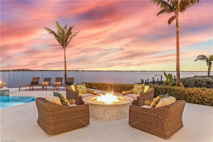 Patio terrace at dusk with a water view and an outdoor living space with a fire pit
