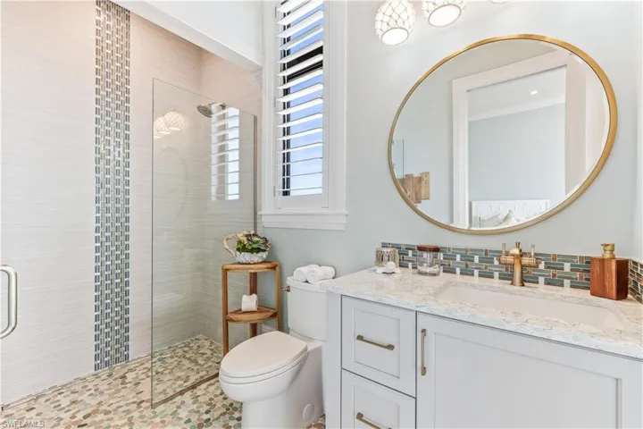 Bathroom featuring vanity, toilet, and a tile shower