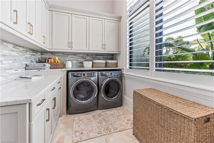 Laundry room with washer and dryer, light tile patterned floors, and cabinets