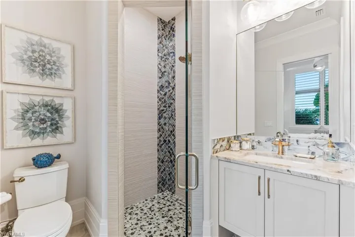Bathroom featuring vanity, toilet, an enclosed shower, and crown molding