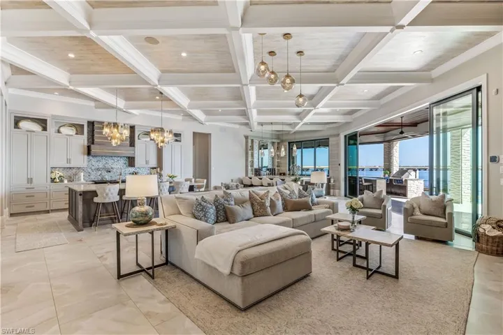 Living room with beam ceiling, ceiling fan with notable chandelier, and coffered ceiling