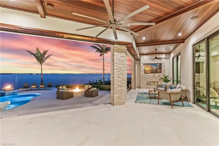 Patio terrace at dusk with a water view and an outdoor living space with a fire pit