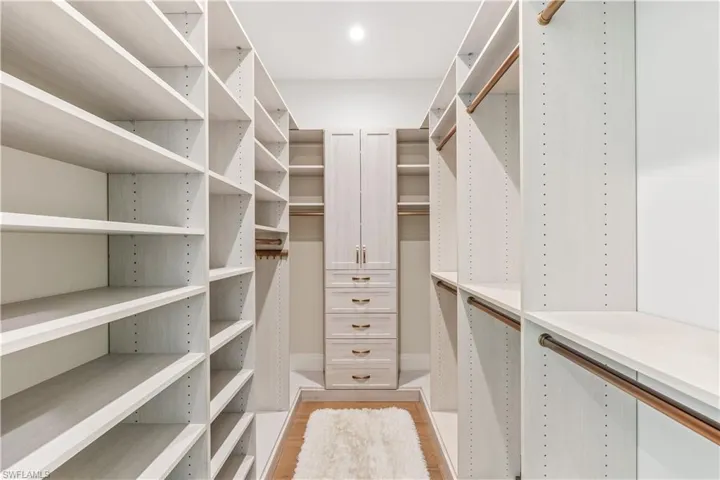 Walk in closet with light hardwood / wood-style floors