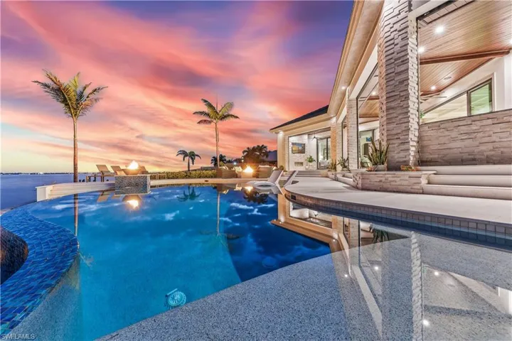 Pool at dusk featuring a water view and a patio