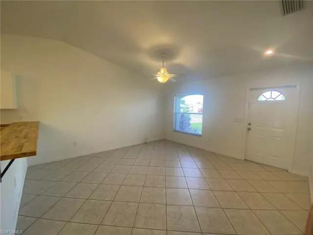 Tiled Living Room with vaulted ceiling and ceiling fan plus counter bar.