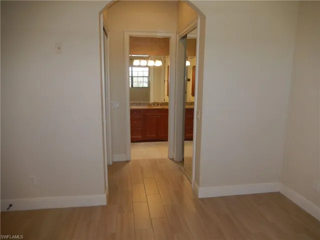 Corridor featuring arched walkways and light wood finished floors