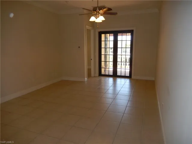 Spare room featuring crown molding, light tile patterned floors, and a ceiling fan