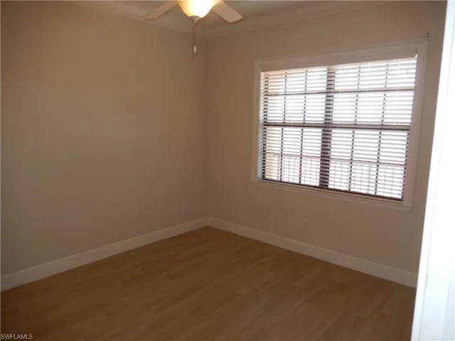 Spare room featuring light wood-type flooring, ornamental molding, and a ceiling fan