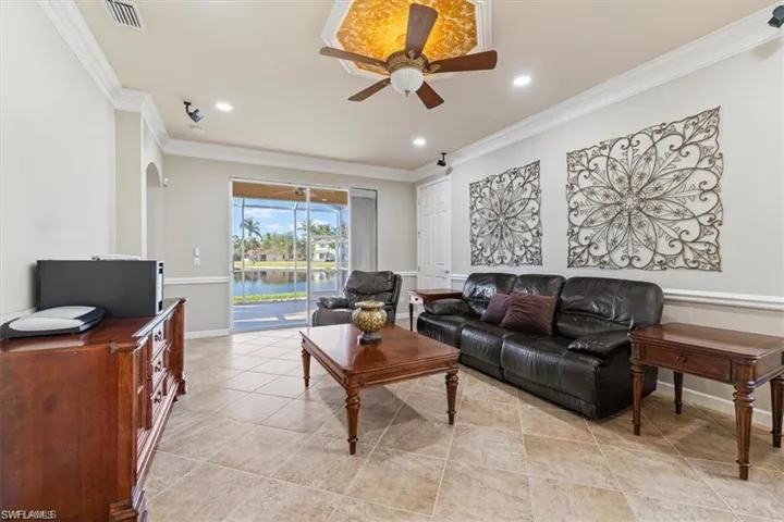 Living room with a ceiling fan, ornamental molding, light tile patterned floors, recessed lighting, and baseboards